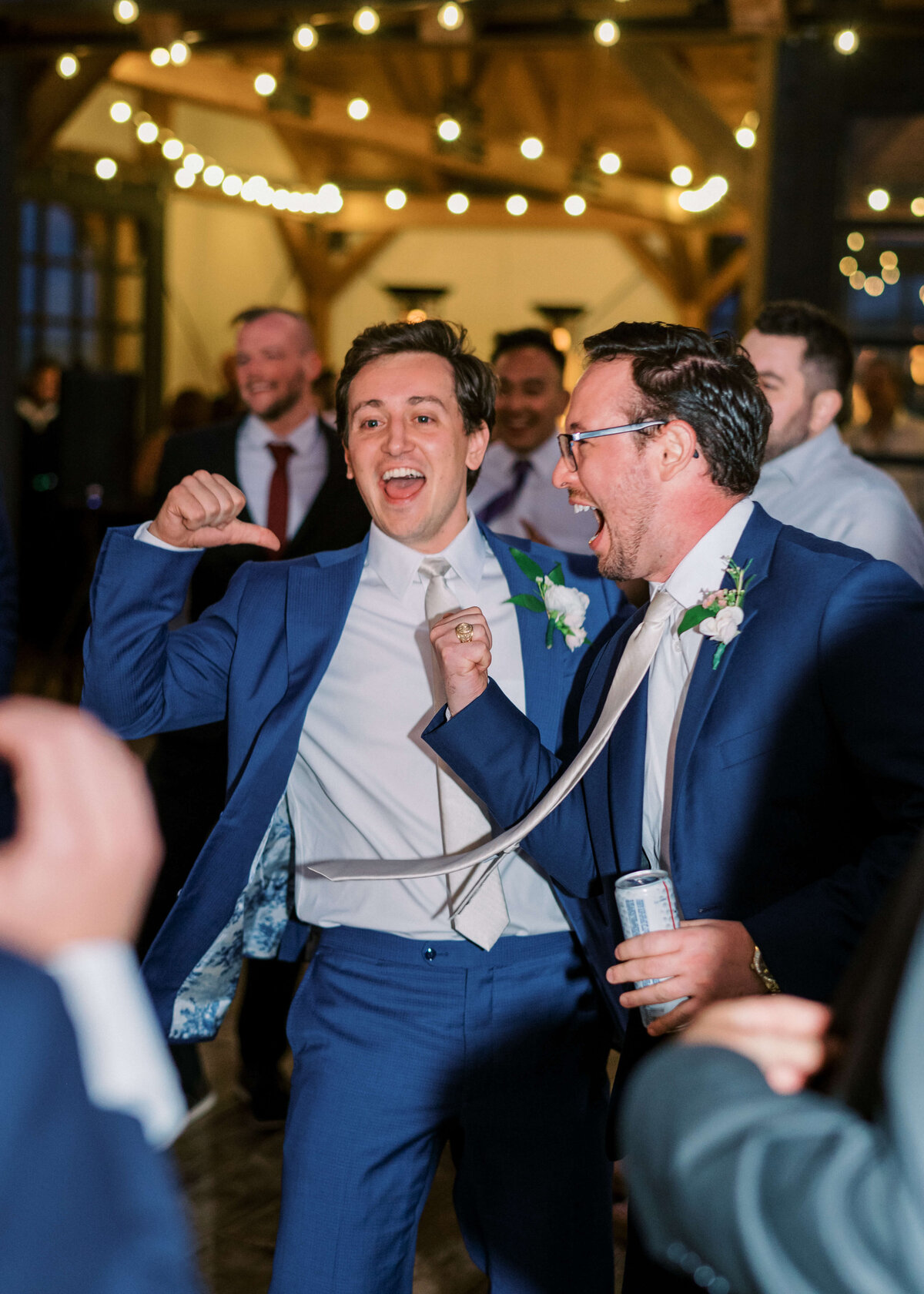 The groom and his friend dance and sing under the stars during a fun reception