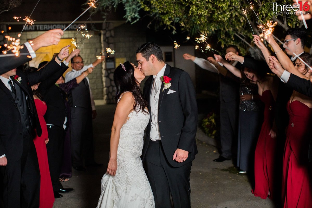 Bride and Groom share a kiss at the end of a sparkler led aisle