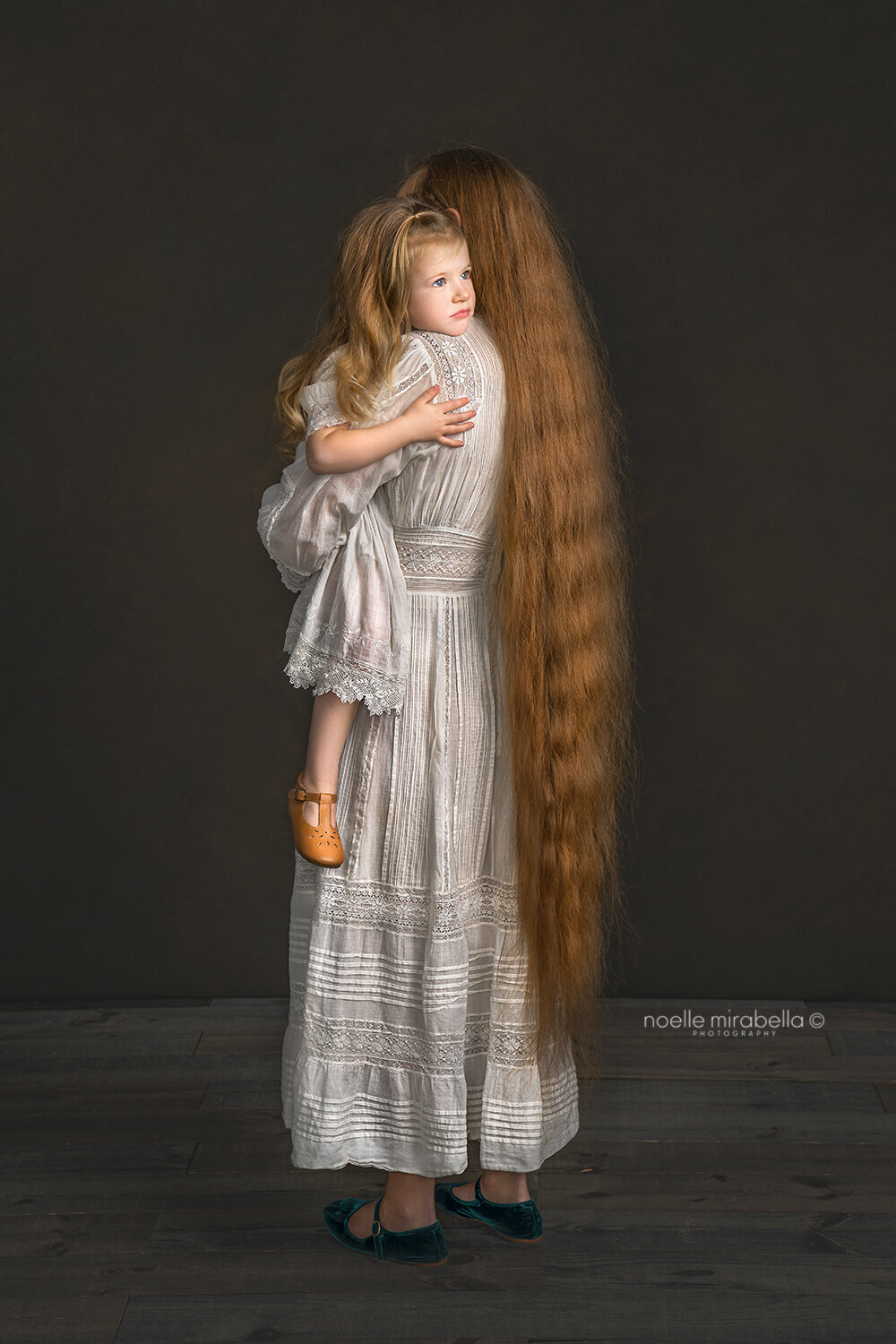 Mother with floor length long hair holding her daughter in her arms.