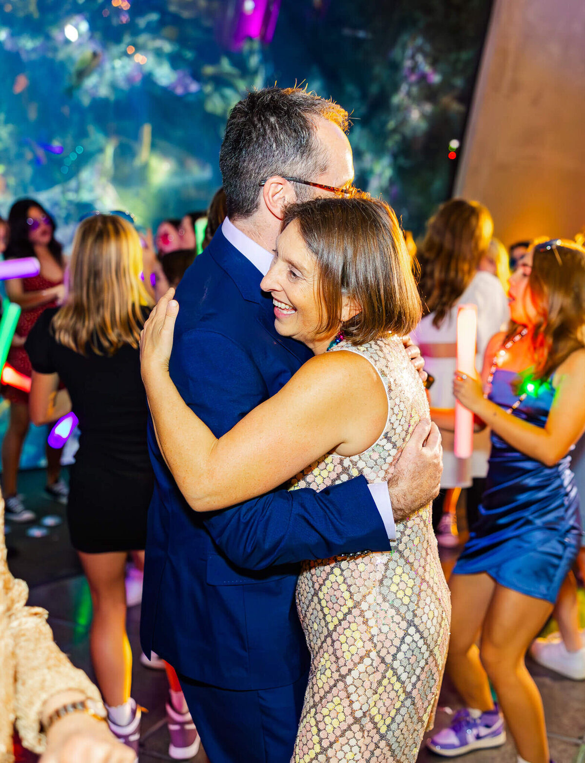Happy parents dance on the dance floor in a blue suit and gold dress