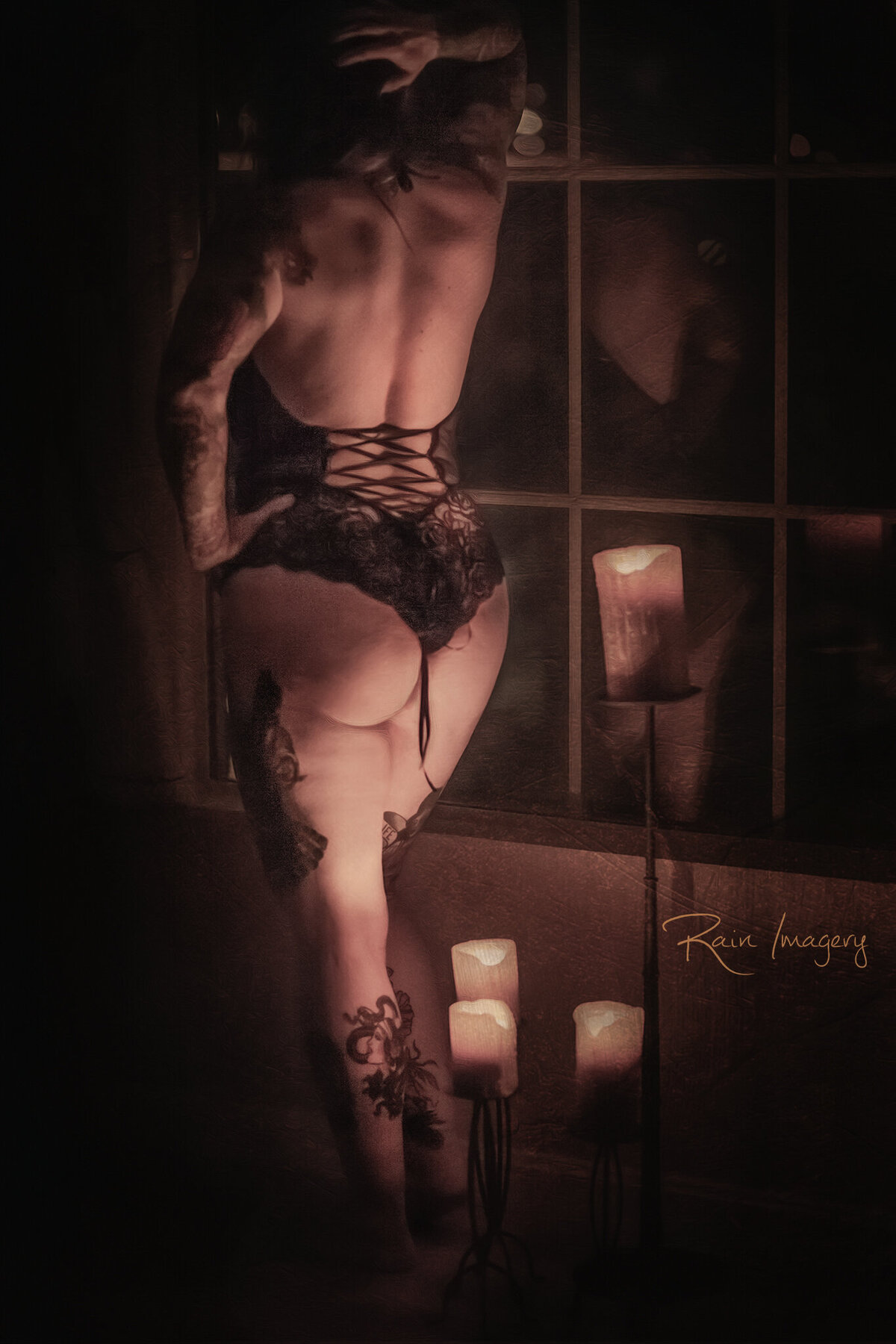 Artsy boudoir image of a woman in a window with candles