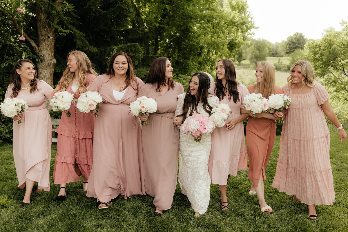 Bridesmaids in blush pink dresses with bouquets.