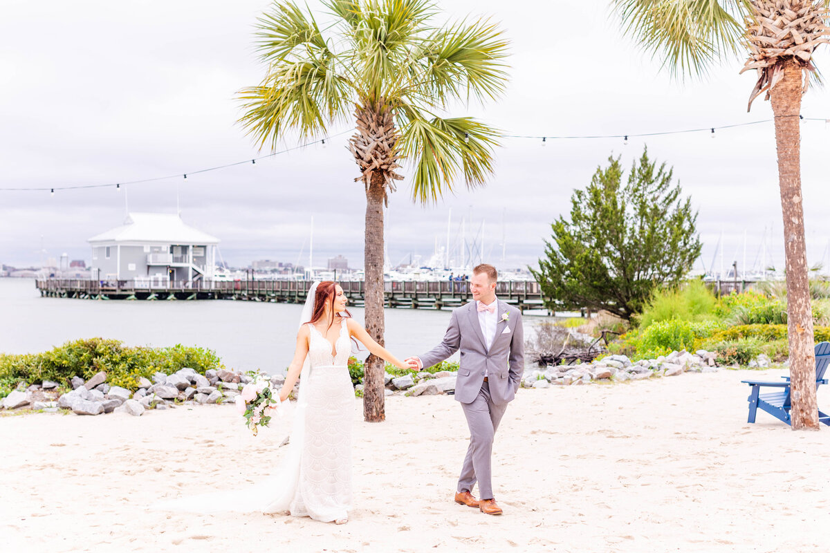 bride and groom holding hands on the beach in charleston