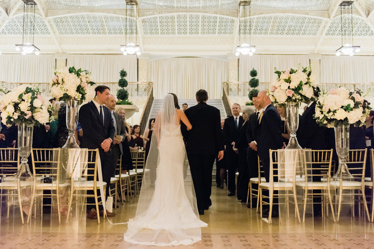 A father escorts his daughter down the aisle during her wedding ceremony at the Rookery in Chicago