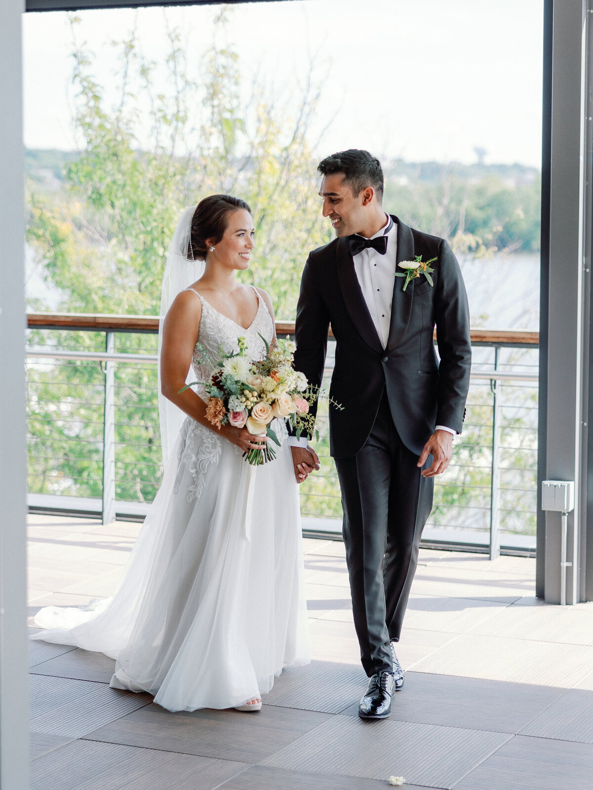A bride and groom look lovingly into each other eyes while they walk across the roof top terrace at district winery in washington dc