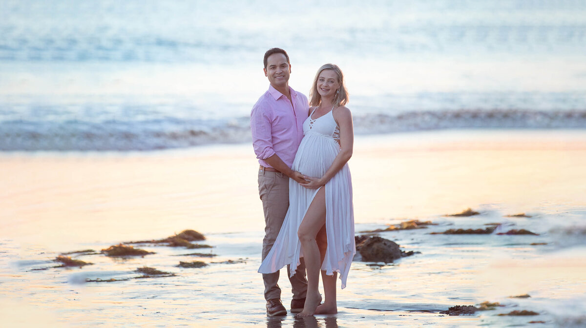 New mom and dad  holding baby bump iat the beach in Malibu by Los Angeles Maternity Photographer