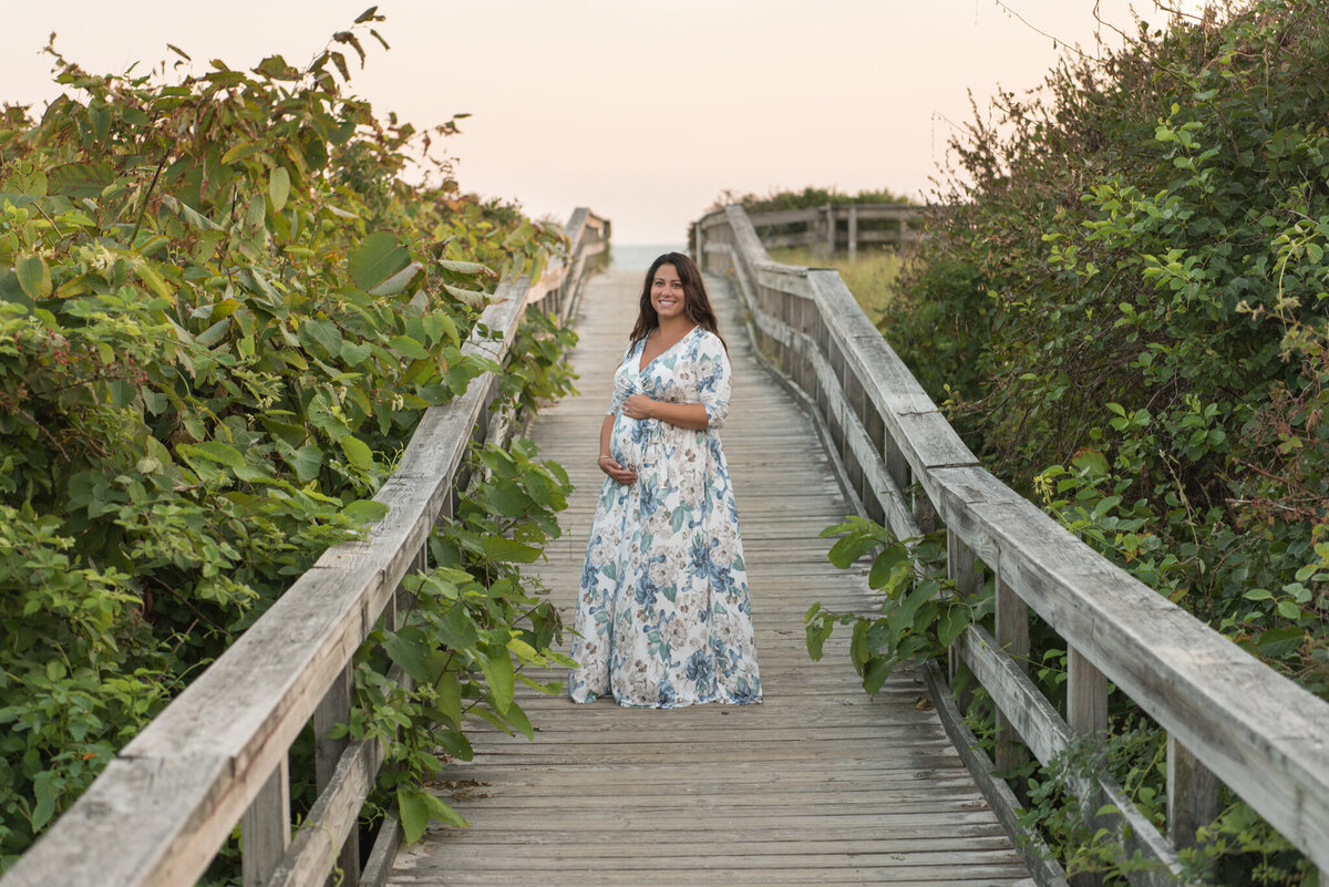 Expecting mother in floral dress standing on board walk