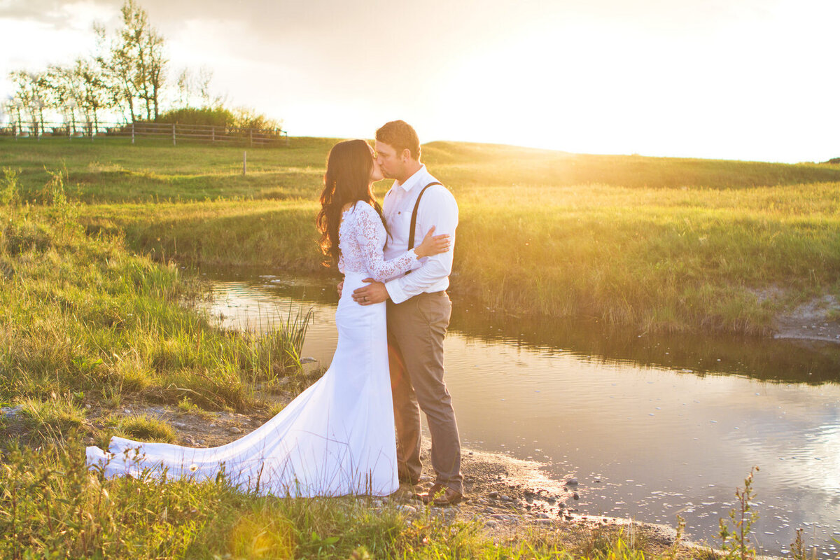 couple standing in a field with a creek behind