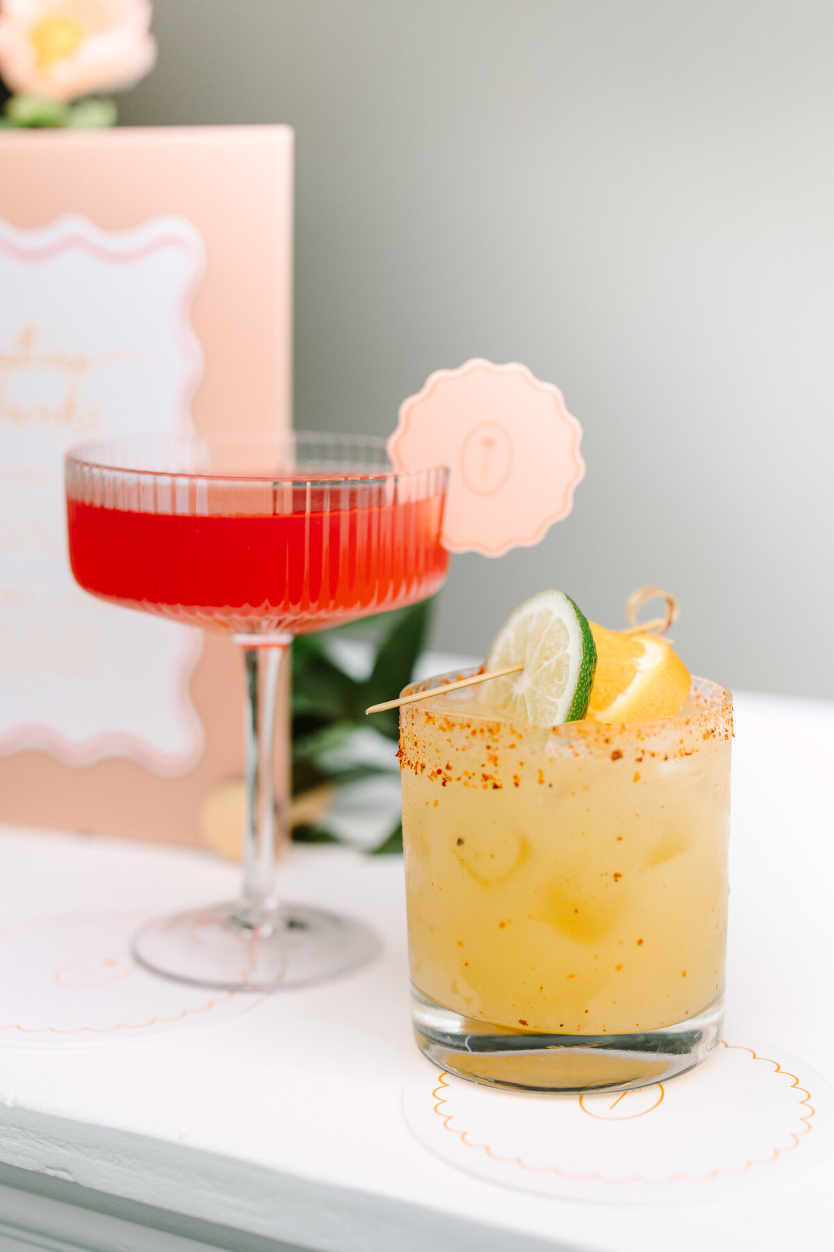 two bright signature wedding cocktails on a bar.