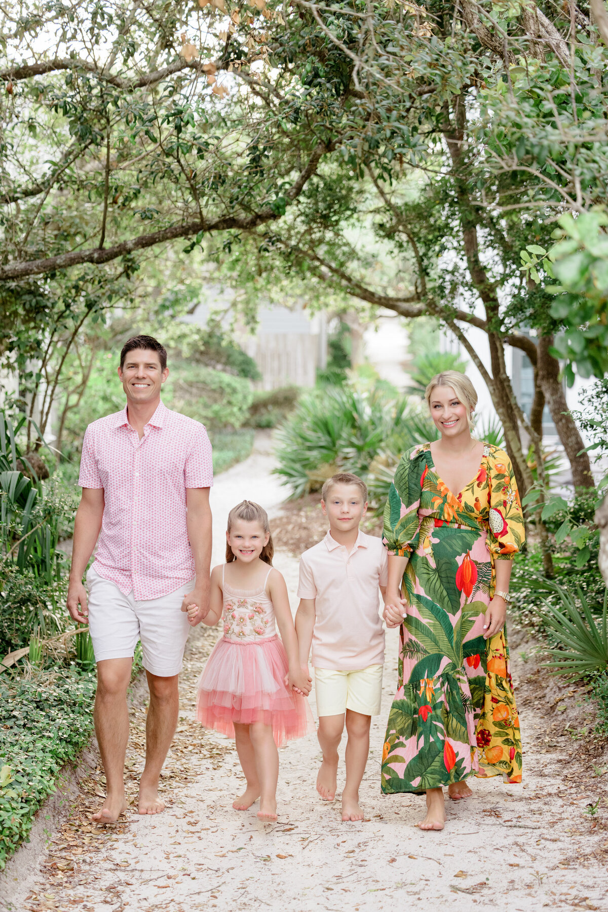 Two parents with two kids in between them walking on a sandy path