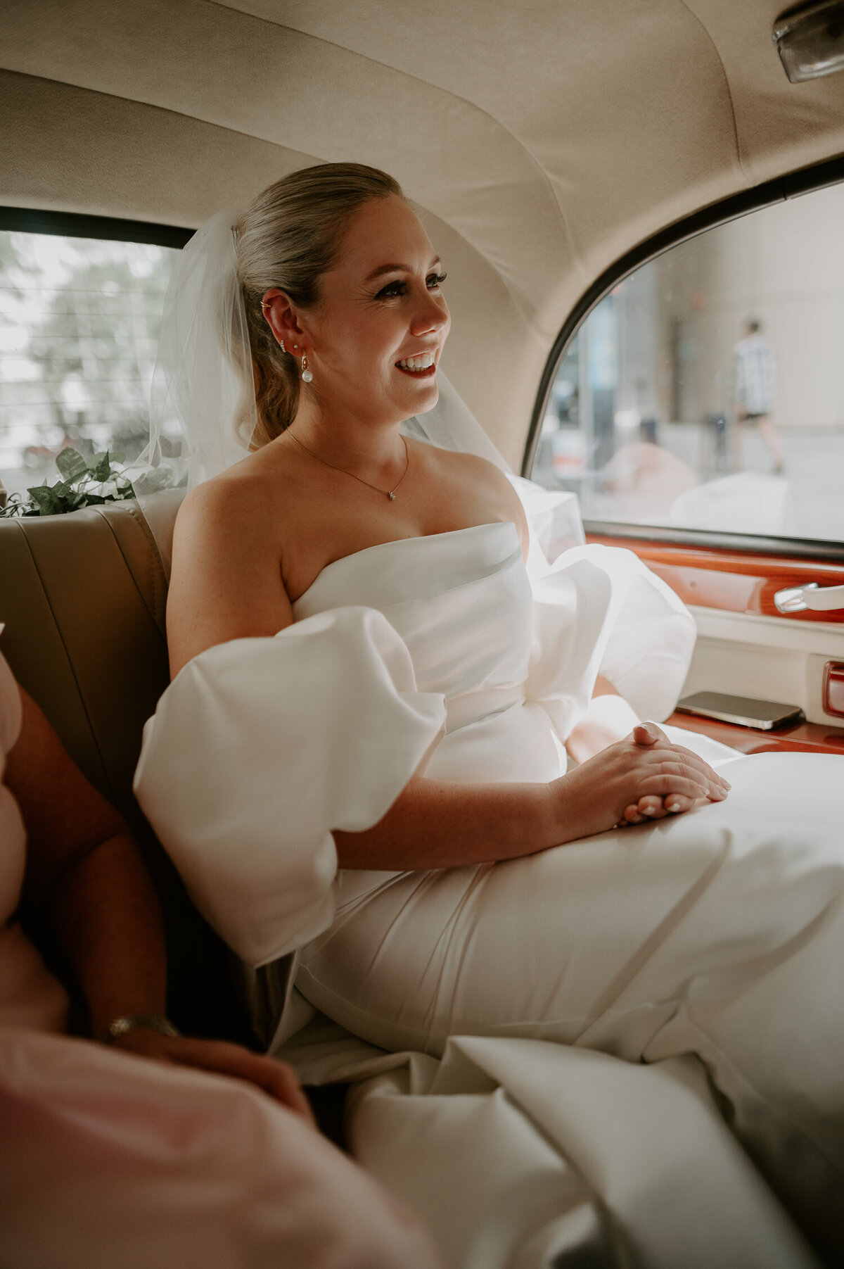 A bride sits in a vintage taxi on the way to 100 Barrington in Brixton, she is wearing a dress with detachable sleeves.