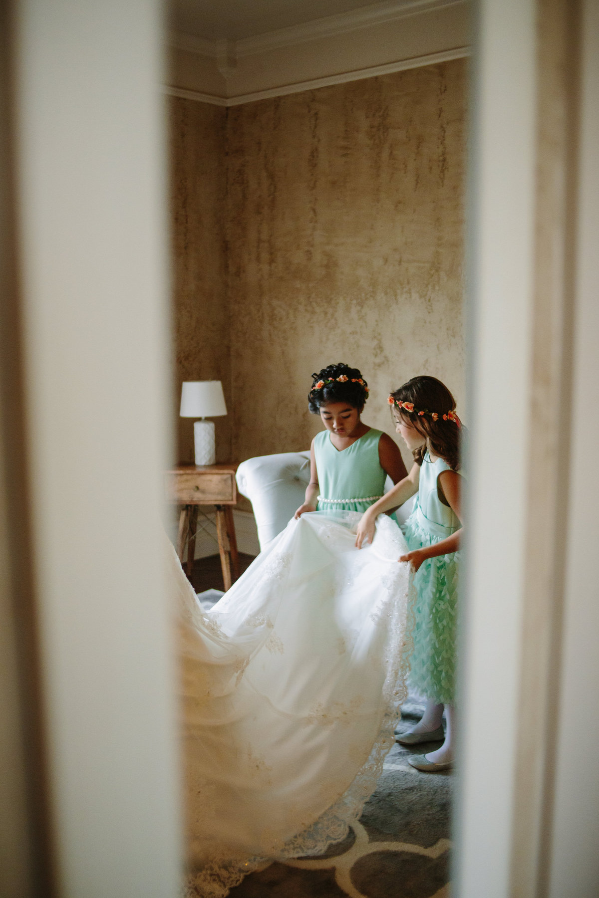 Flower girls checking out bridal gown before wedding while getting ready
