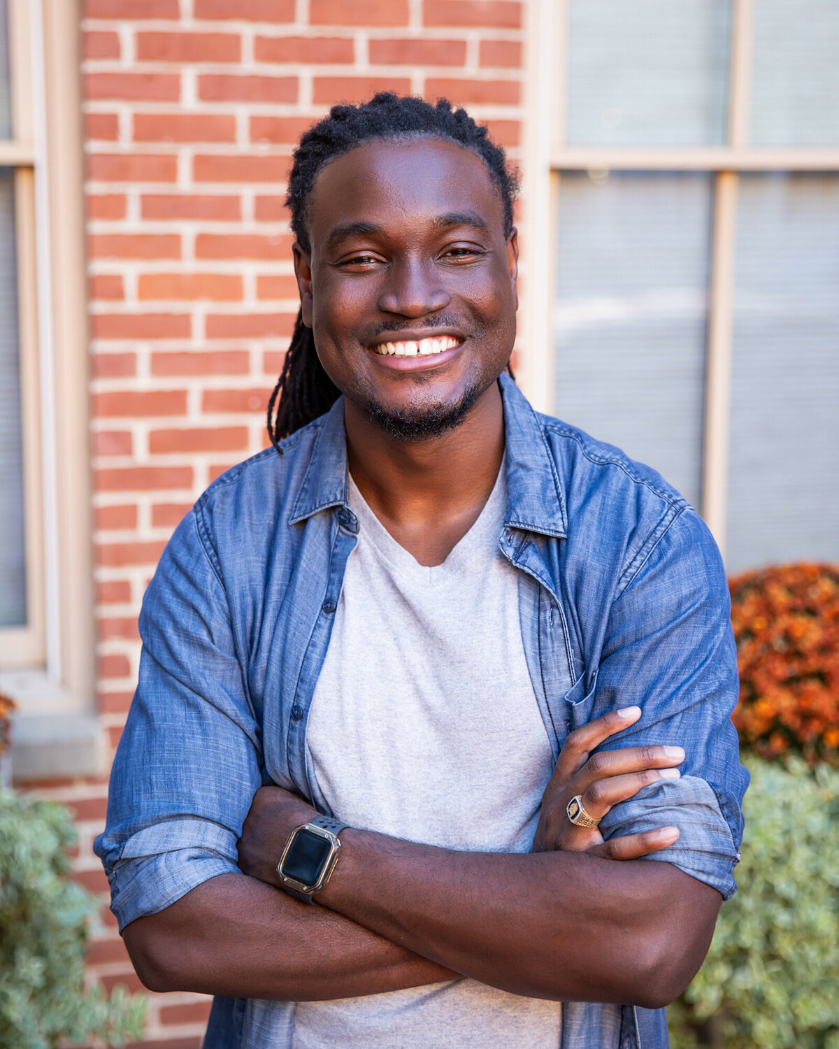A-black-baltimore-man-smiles-during-branding-headshots-in-harbor-east-during-his-photoshoot-with-Ingrid-Berrios-Photography