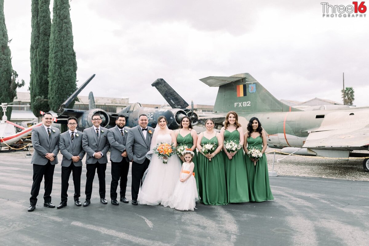 Bride and Groom pose with their bridal party with classic airplanes behind them