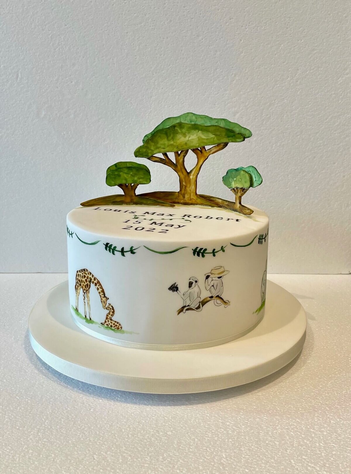A hand painted cake with animals and a model of trees on top