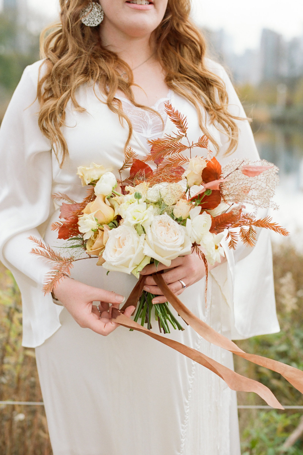 bride holding rustic fall bouquet with flowing ribbon