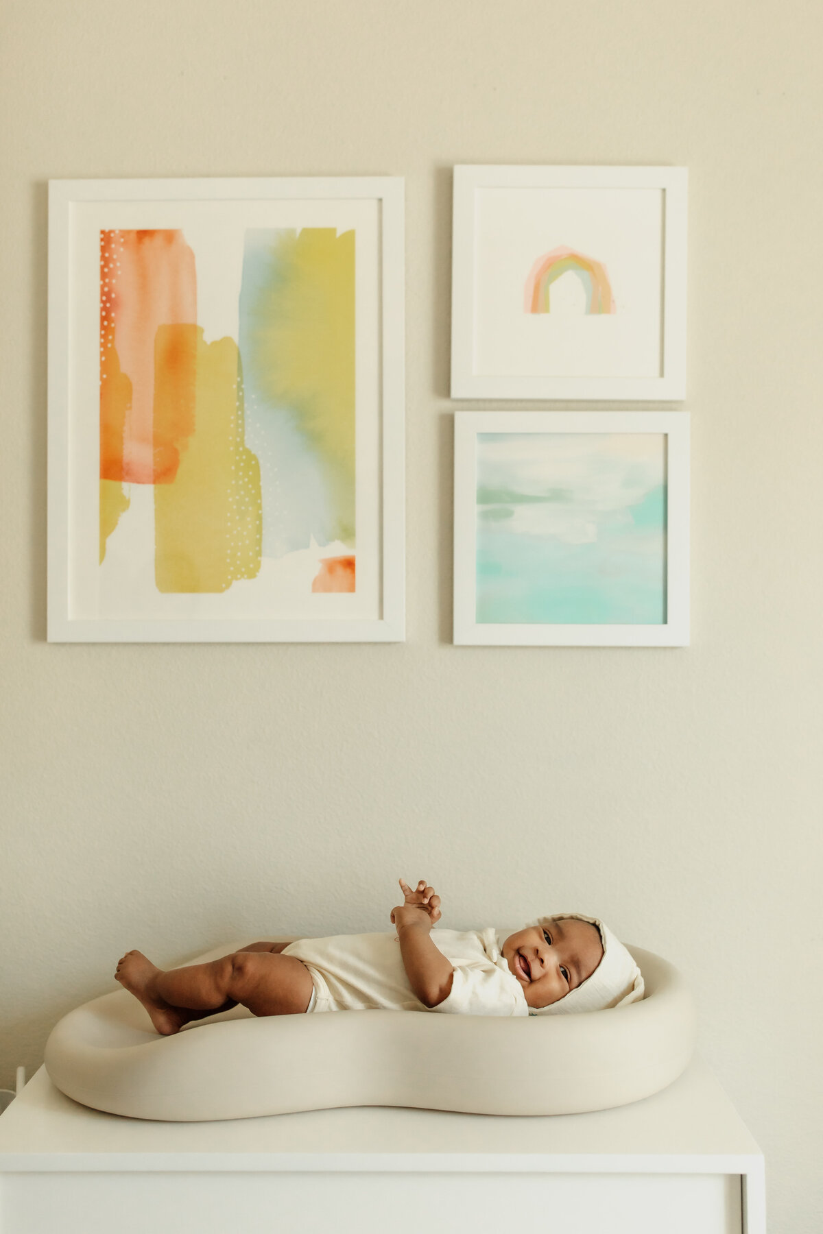 Bay Area in home family photography session of baby on changing table with pastel artwork above