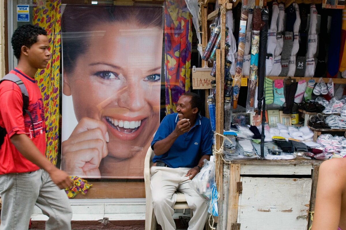A man laughs with poster of women laughing behind him on Street in Bogota Columbia