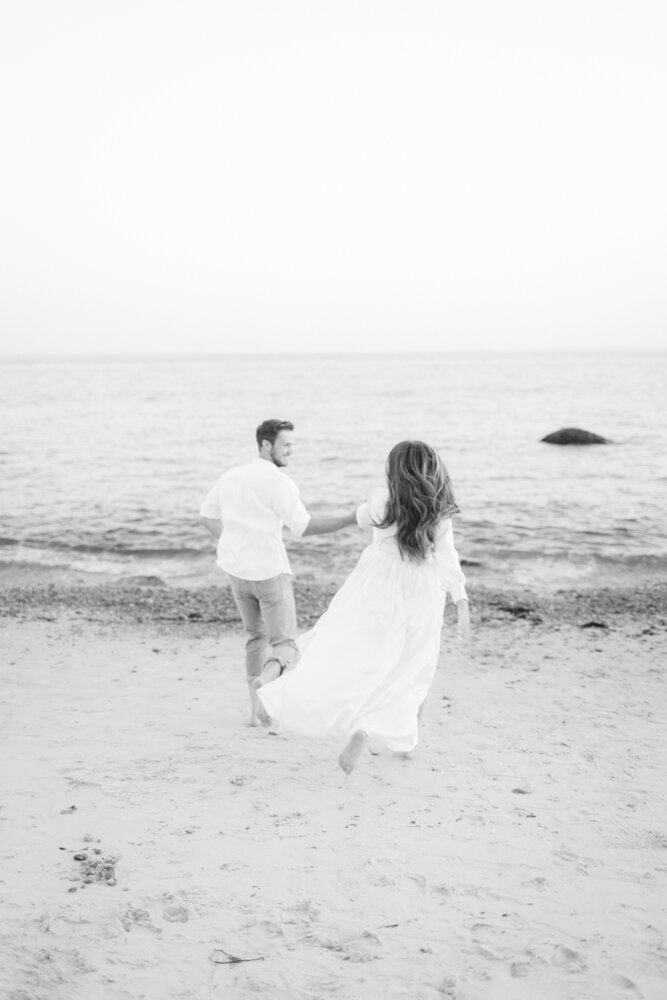 black and white portrait of couple running together on the beach