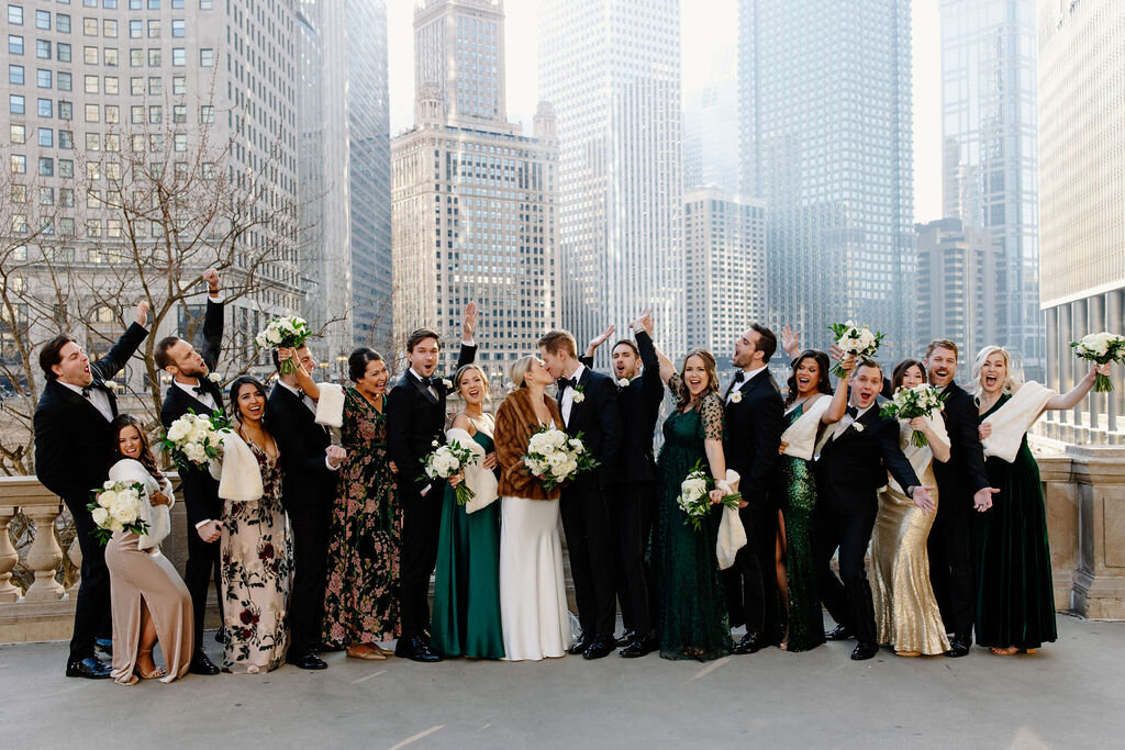 Bridal party cheers on newly married bride and groom as the kiss, overlooking Chicago skyline,