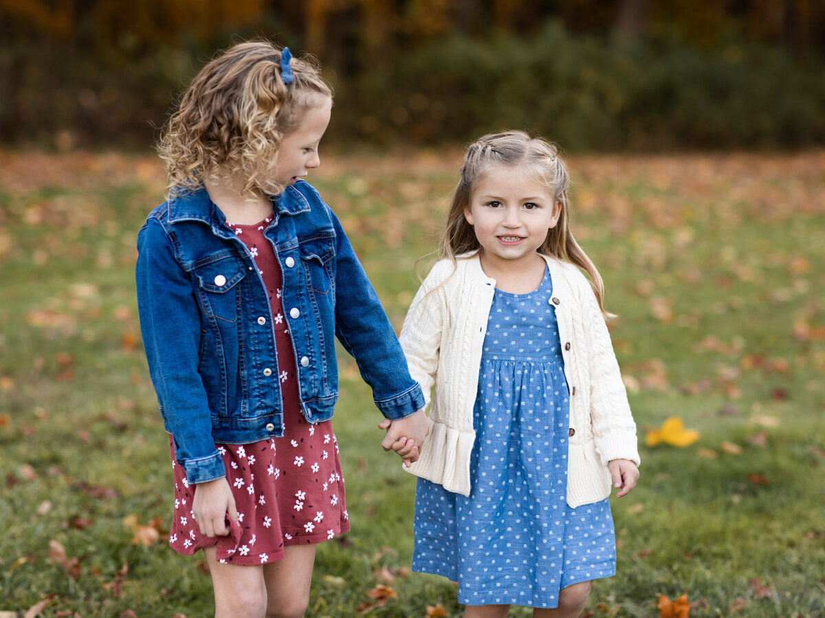 sisters holding hands for family photos at the park