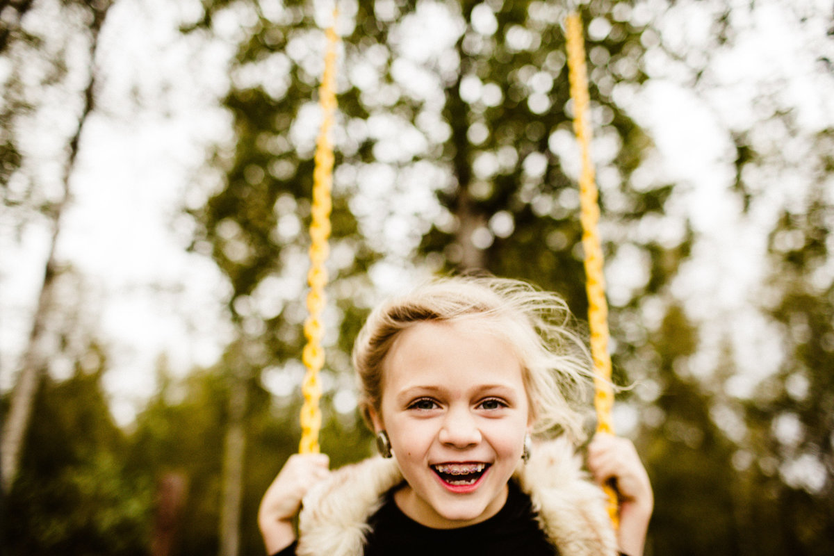 young girl laughing on swingset