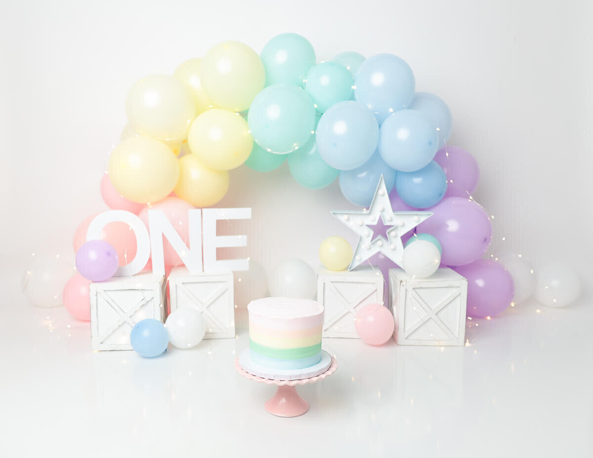 A decorated cake surrounded by pastel balloons in Rochester, NY.