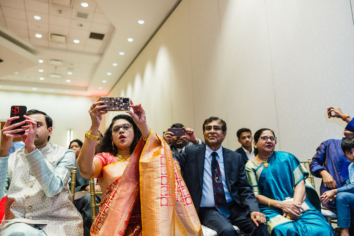 Guests at an Indian wedding ceremony using their phones to capture the event