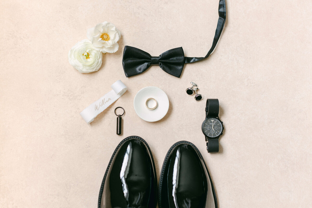 Shoes and a black tie sit on a white background.