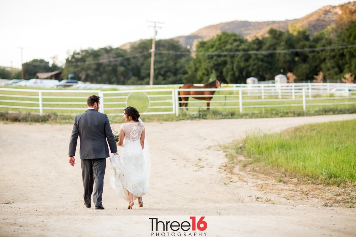 Bride and Groom walk away on a trail hand in hand