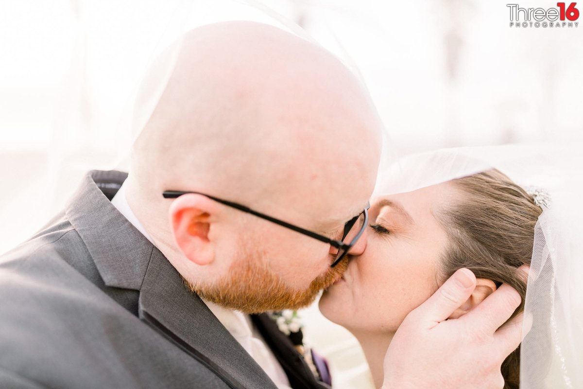 Romantic kiss as the Groom holds his Bride's head during an intimate moment
