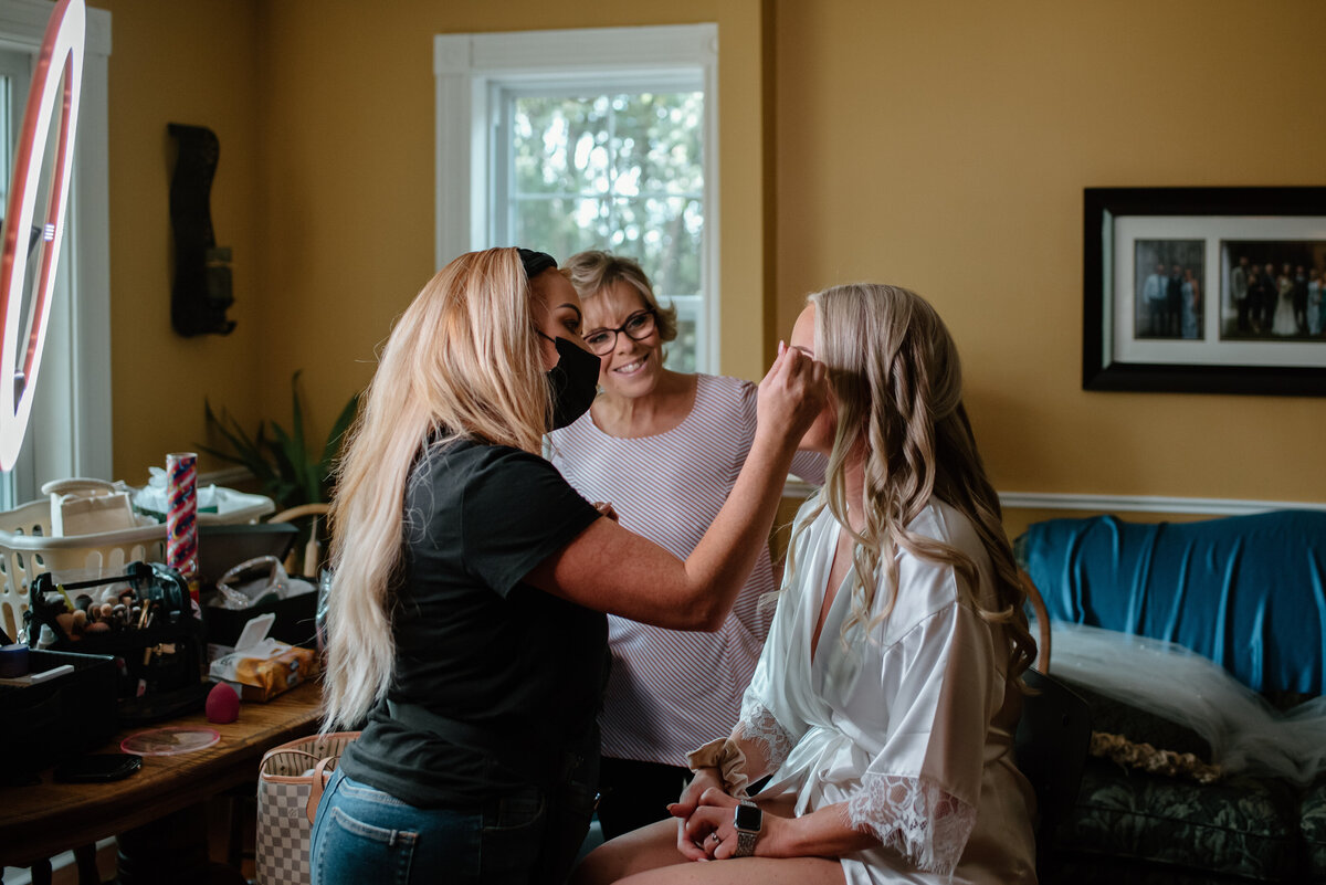 bride has makeup applied as mother smiles