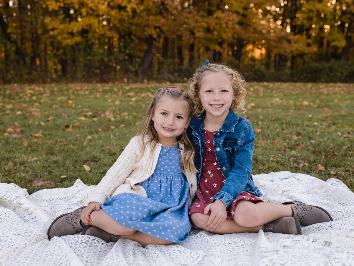 sisters sitting on lace blanket for family photos
