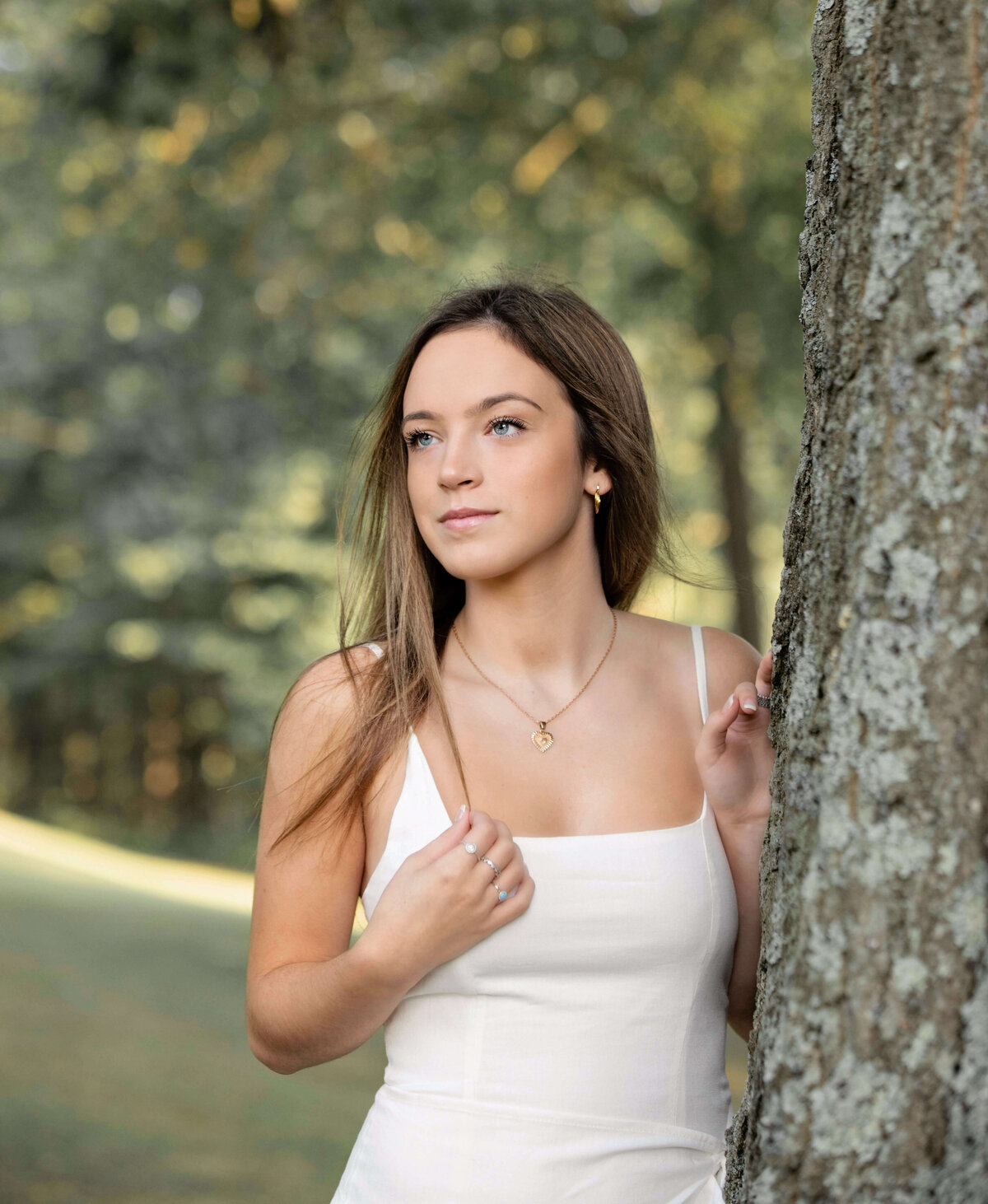Senior photo of a girl in a white dress leaning into a tree at Wintergreen Gorge in Erie Pa