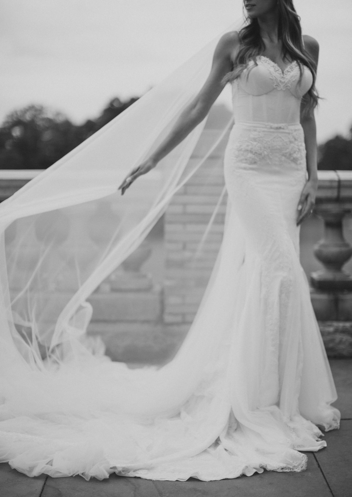 bride wearing strapless wedding gown and watching veil in wind during Philadelphia wedding photography