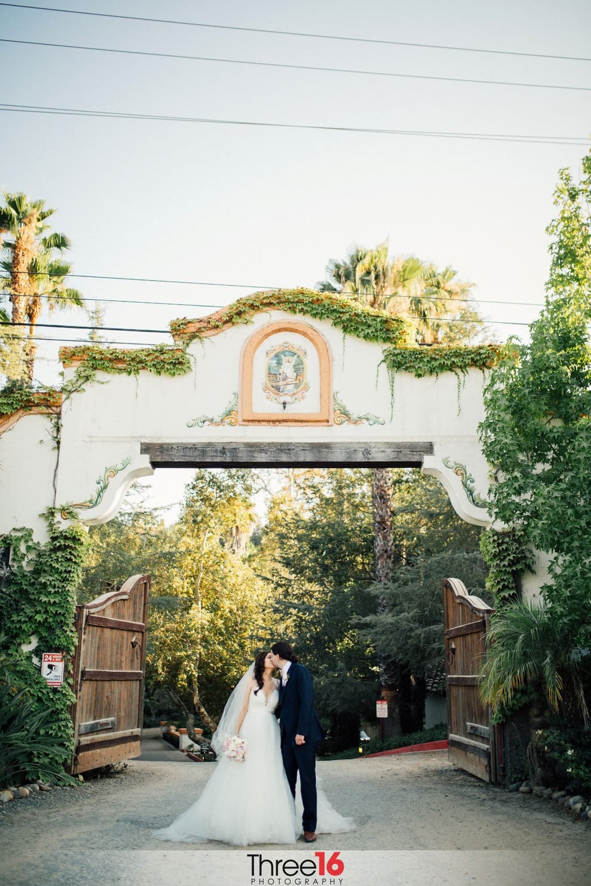 Bride and Groom kiss at the gate entry to Rancho Las Lomas wedding venue