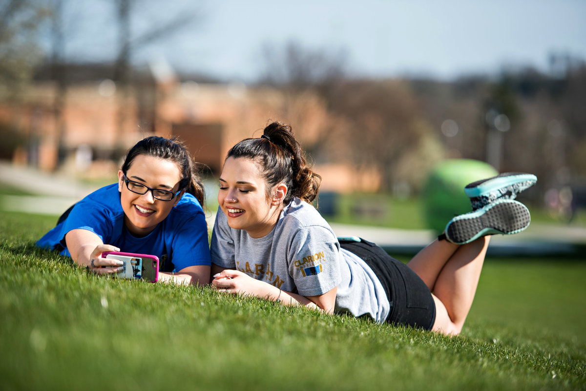 Senior portraits of two twins laying in the grass.