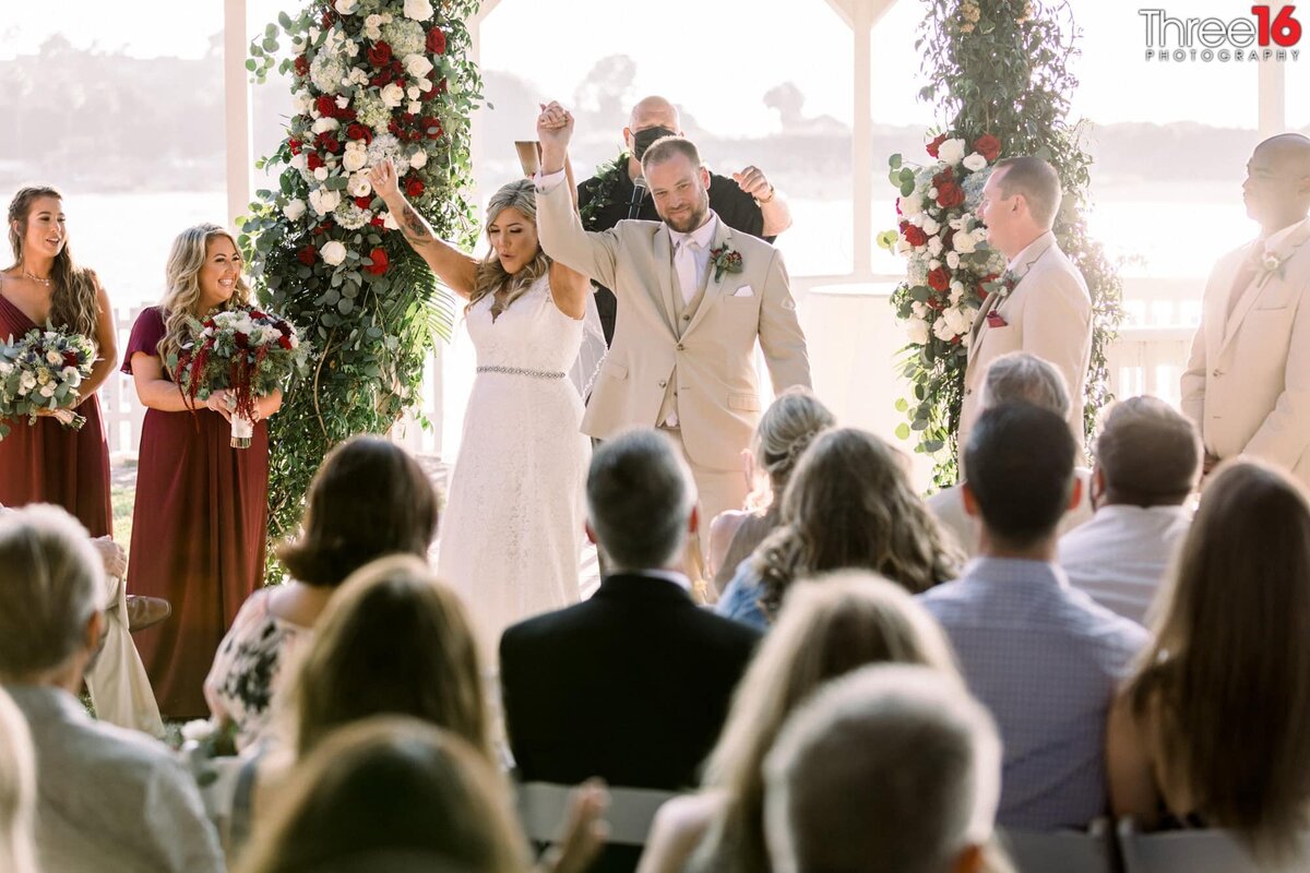 Bride and Groom face their guests with their arms in the air as they are announced