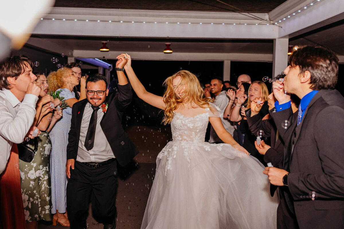 photo of a bride and groom happily running through a tunnel of wedding guests