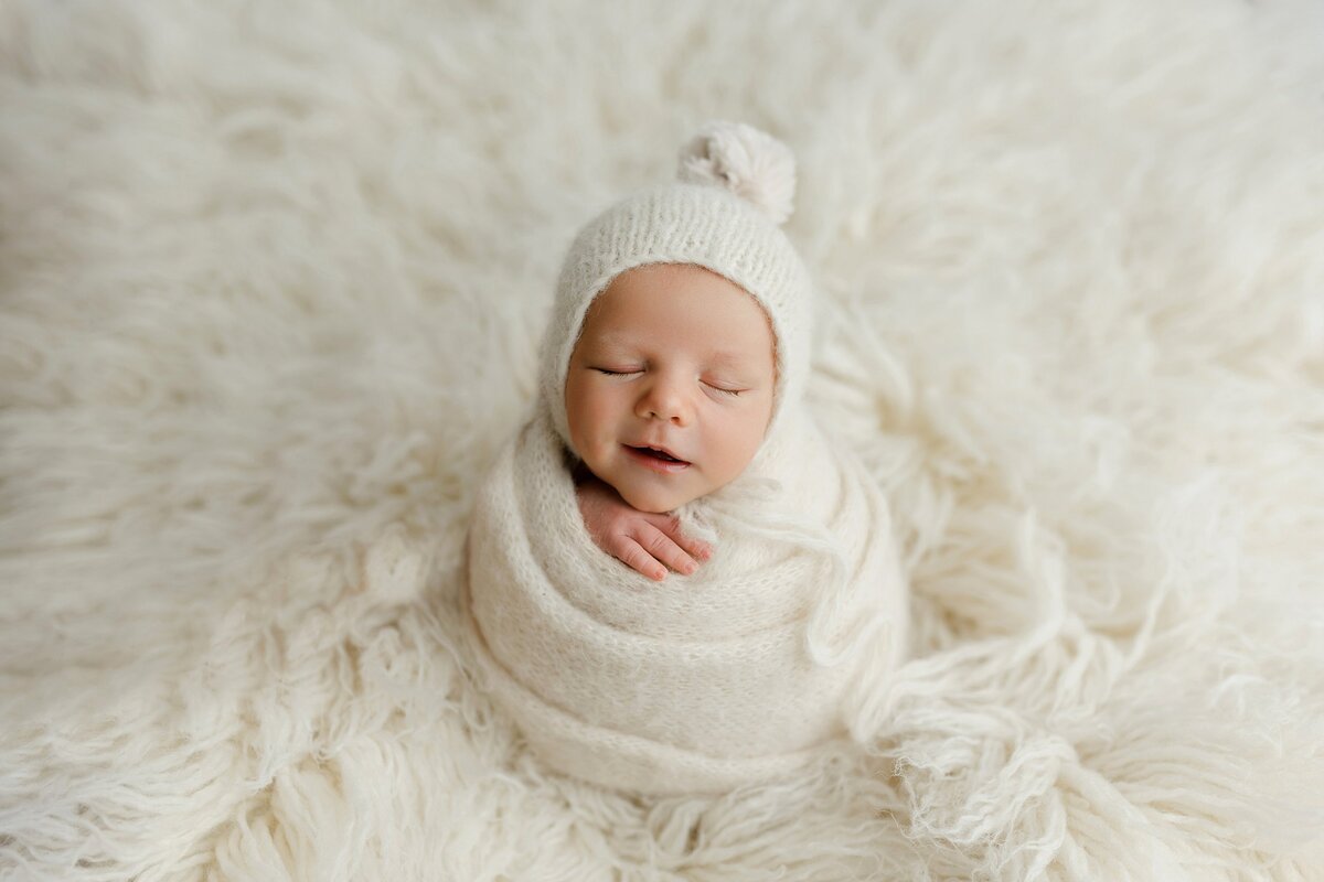 Newborn baby boy in a tight wrap smiling in Sprinville Alabama studio