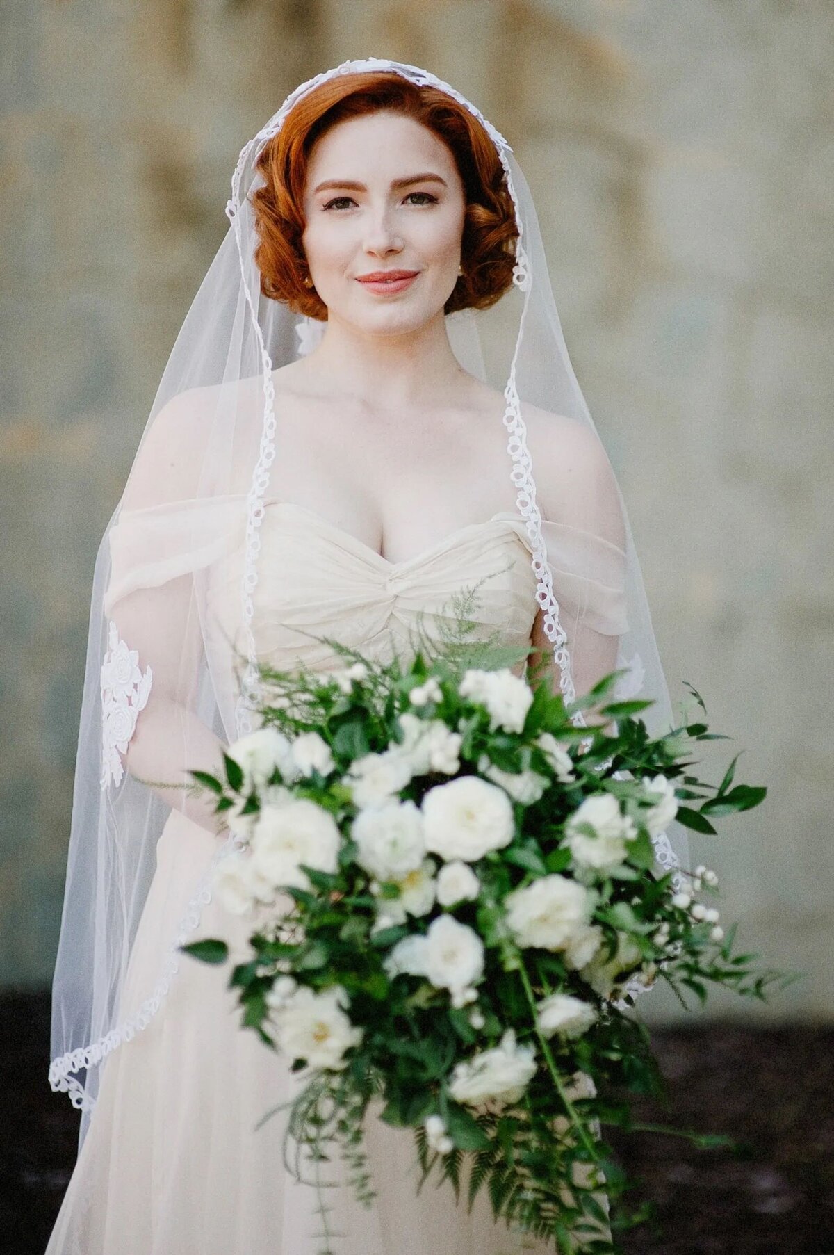 A bride holding a large bouquet of flowers.