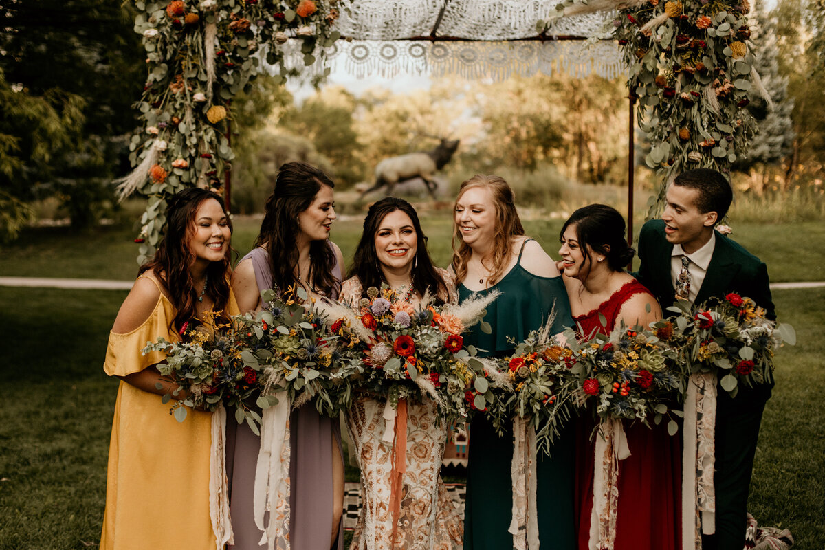 bride with bridal party looking at each other smiling