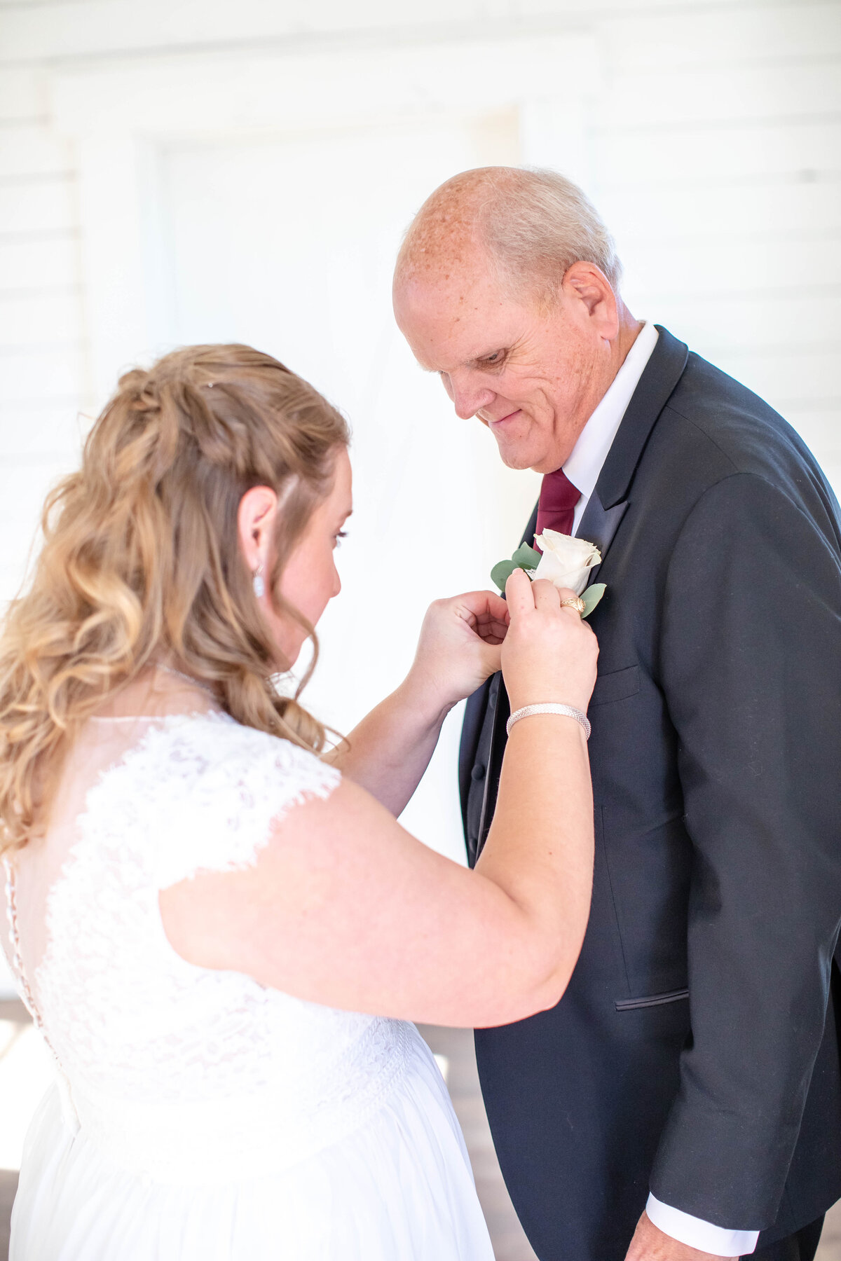 bride secures father's boutonere  at Morgan Creek Barn wedding in Dripping Springs Texas