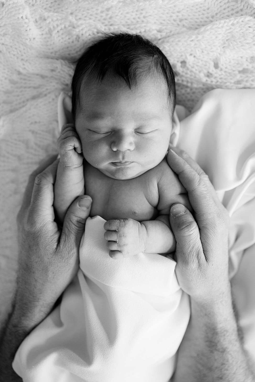 black and white newborn photo with hands on baby