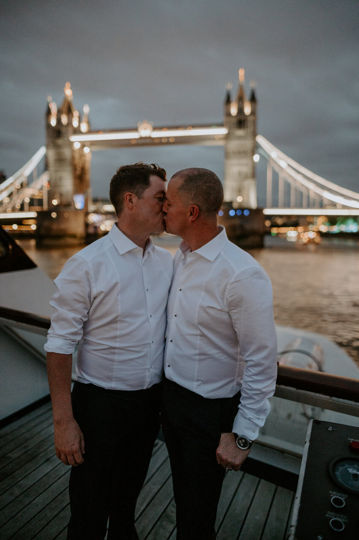 Married at Marylebone Town Hall and then onto The Silver Sturgeon for their reception, these two grooms kiss under a night sky in London as they go under Tower Bridge on the Thames.
