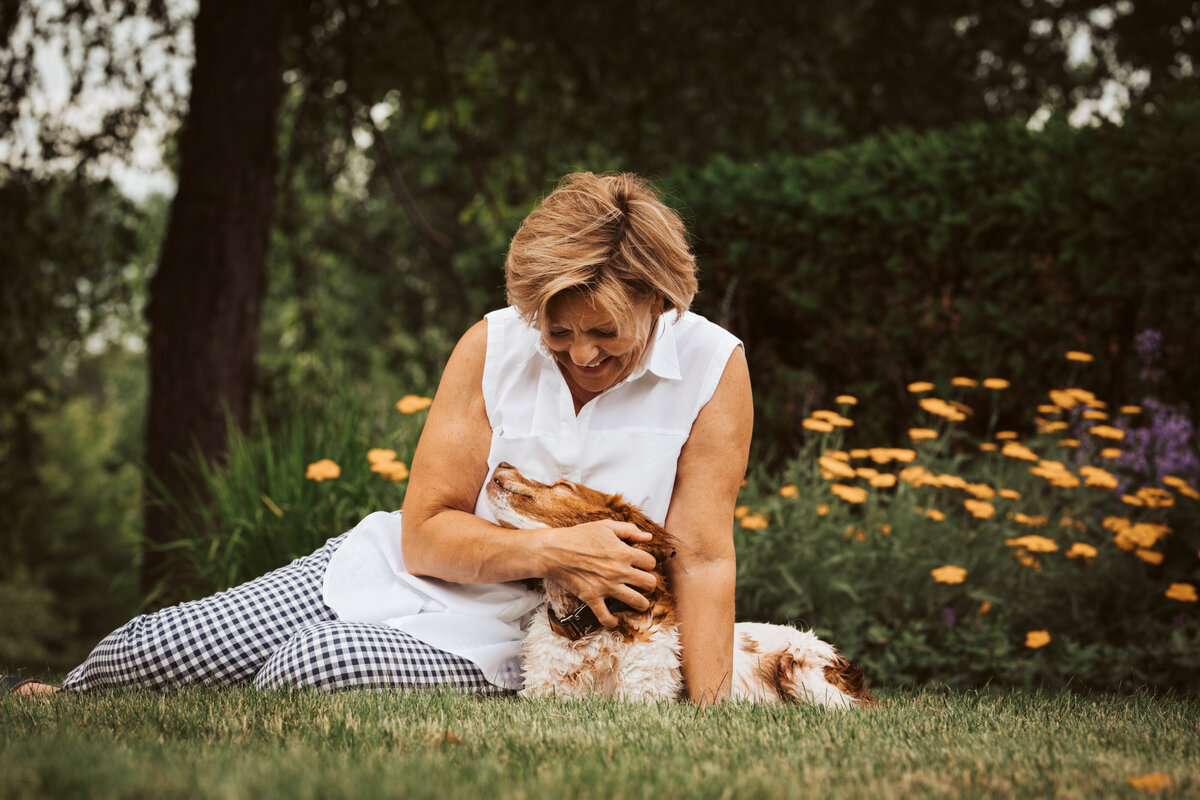 Mom snuggles with dog in front of summer flowers Vermont Dog Photographer