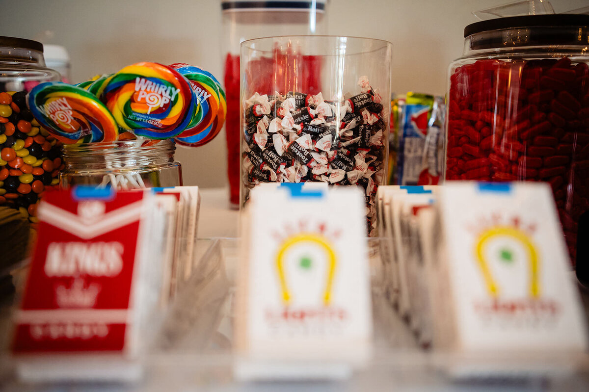 A candy bar with a variety of sweets, including Whirly Pops, Tootsie Rolls, and other assorted candies, displayed in clear containers.