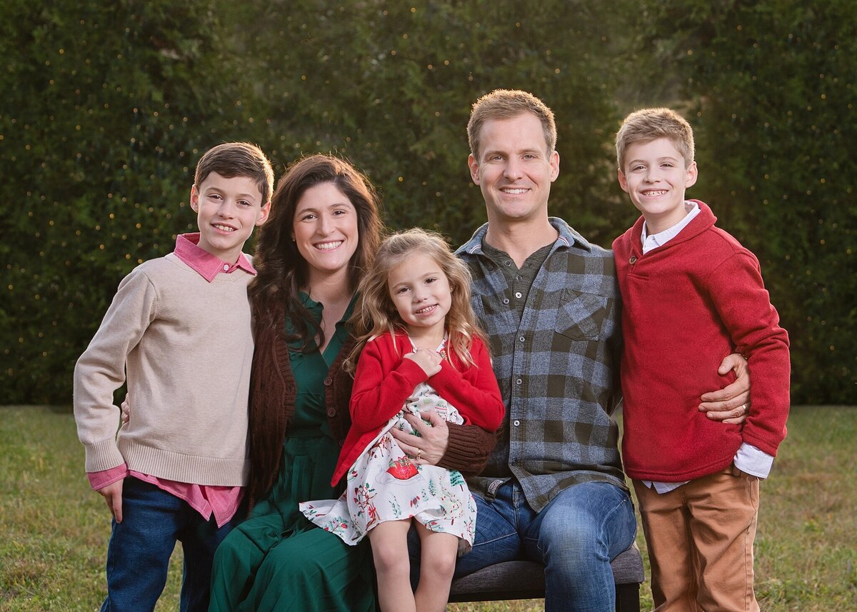 family of five in fall colors in front of pines and christmas tree lights
