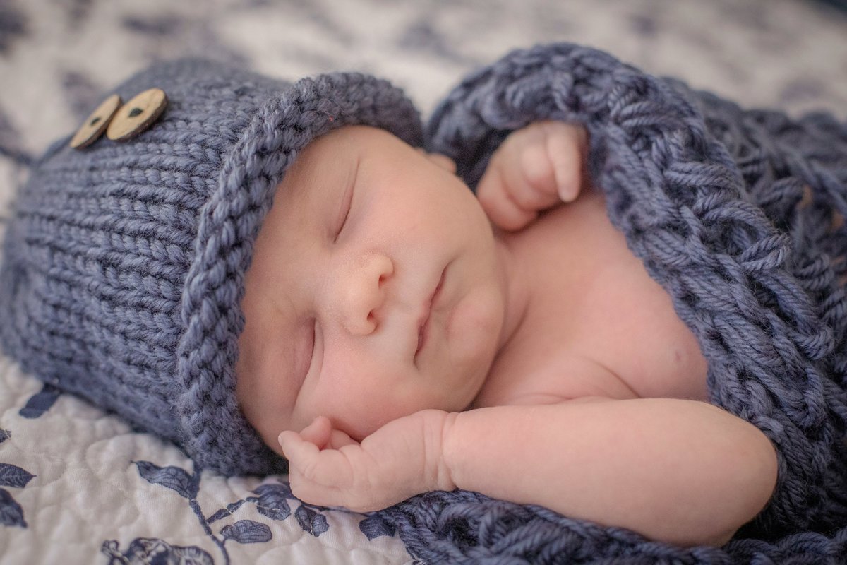 newborn baby in blue knit hat and blanket
