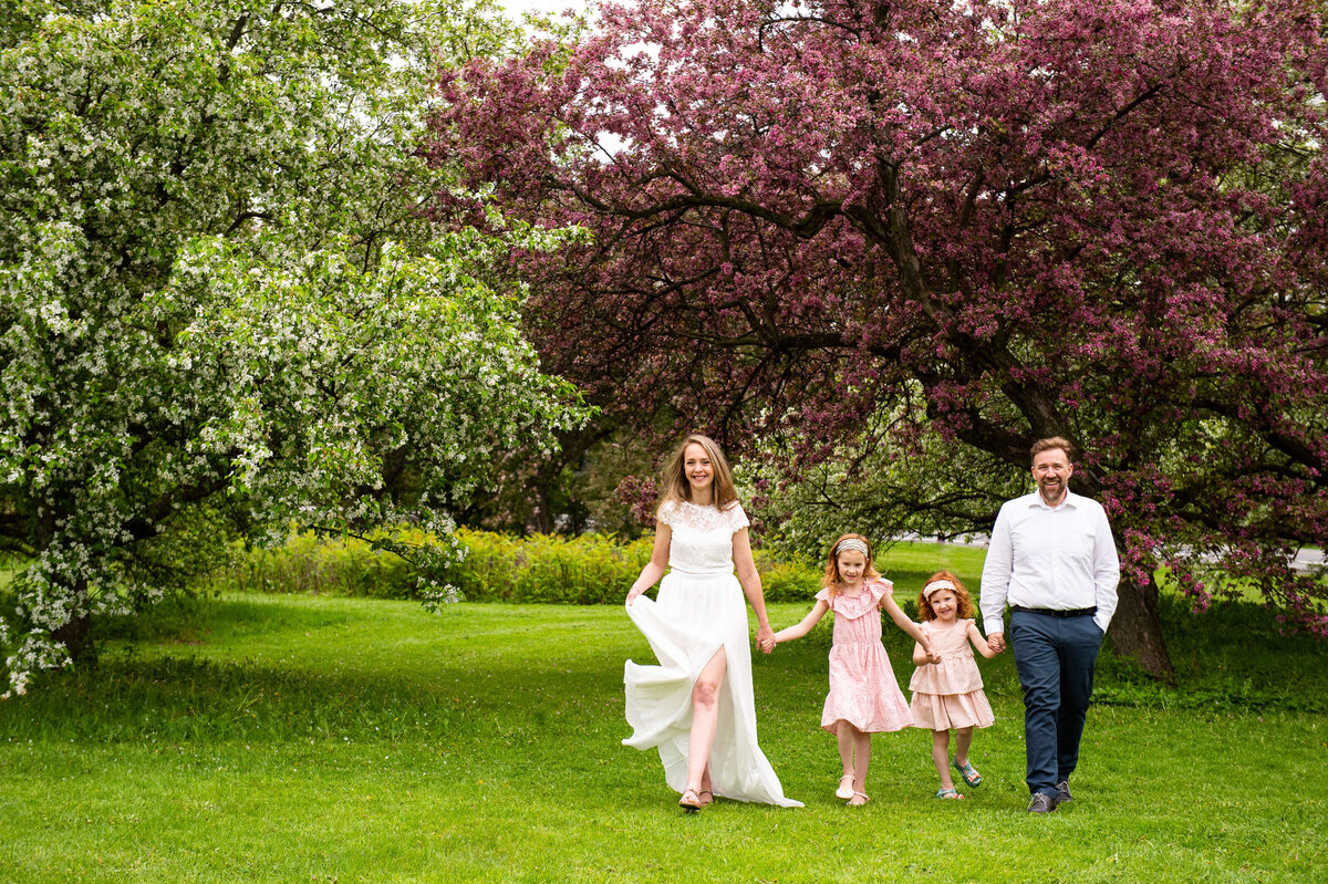 a mom and dad walk with their children in the blossoms captured by Ottawa Family Photographer JEMMAN Photography